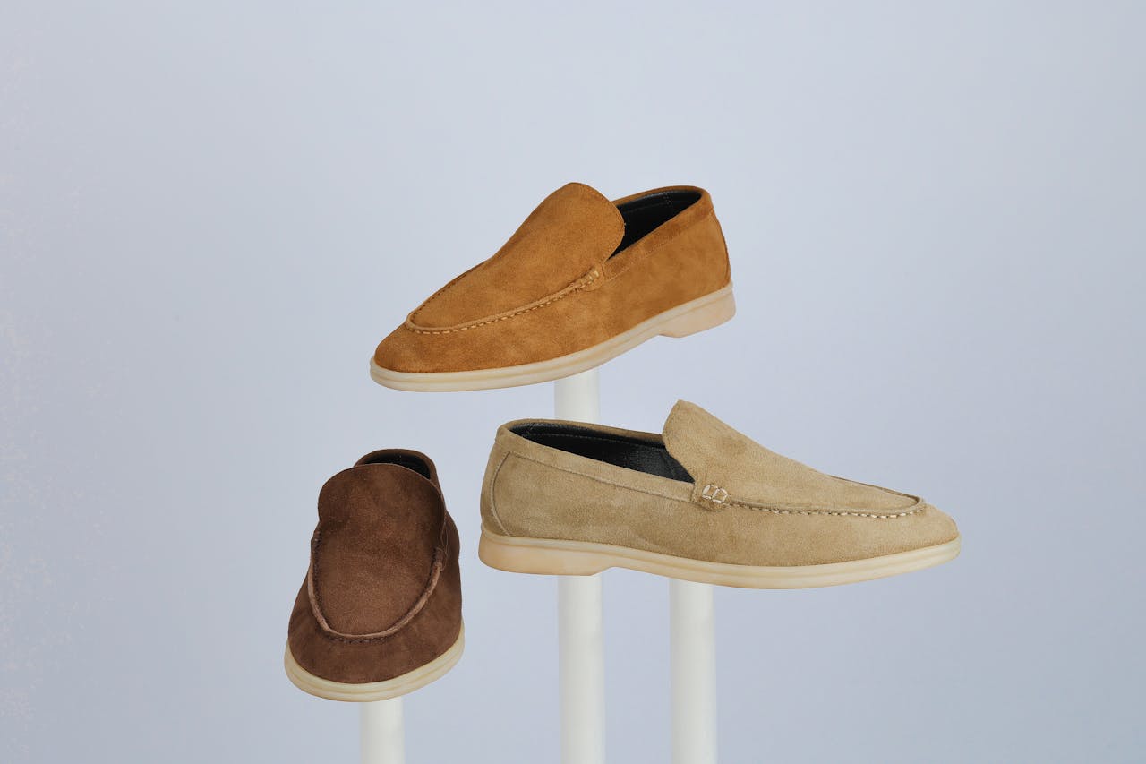 Three suede loafers showcased on stands, highlighting style and elegance.
