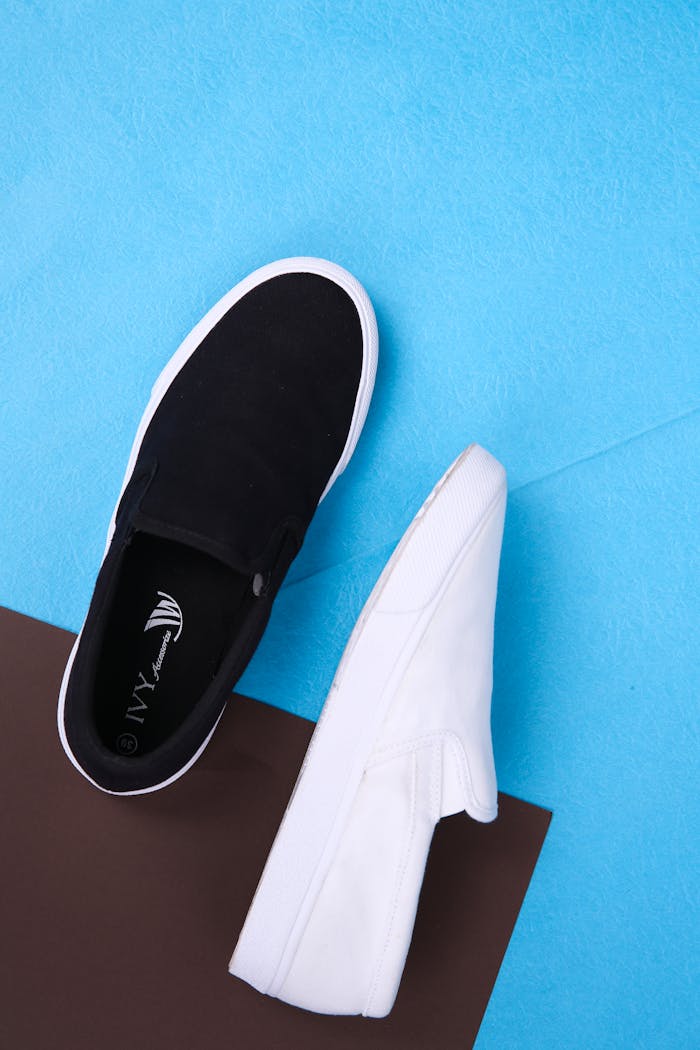 Stylish black and white sneakers arranged on a blue and brown background, perfect for fashion themes.